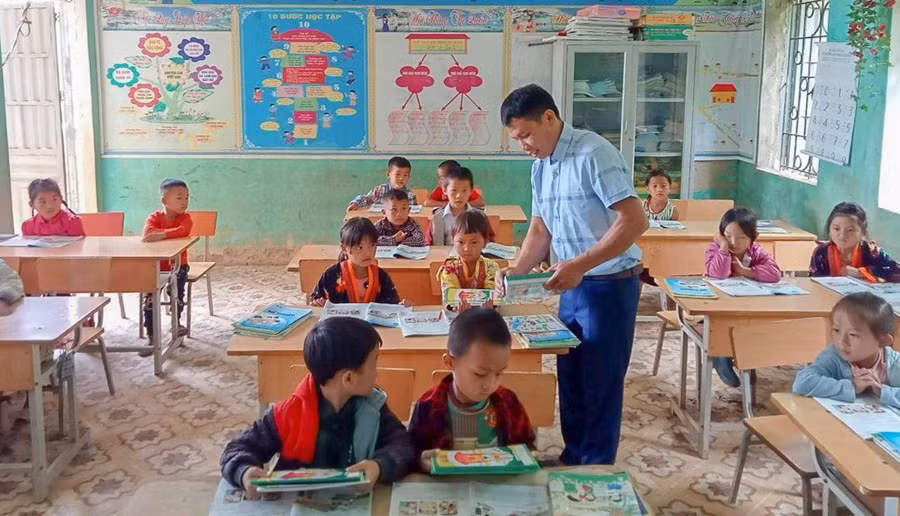 Thầy Lò Văn Thoàn phát sách mới cho học sinh trong buổi đầu tựu trường.