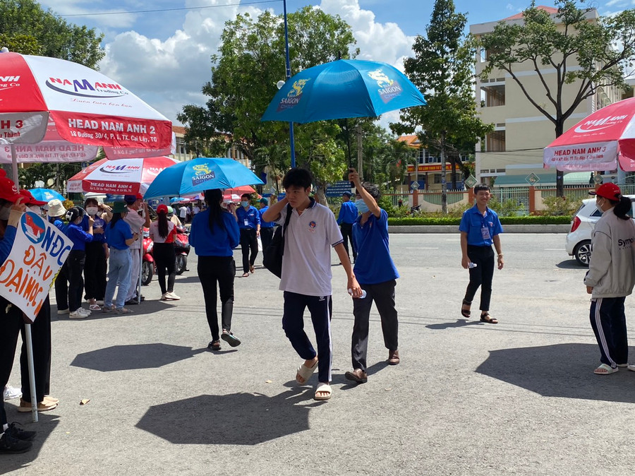 Tình nguyện viên che ô cho thí sinh vào trường thi. Tình nguyện viên che ô cho thí sinh vào trường thi.