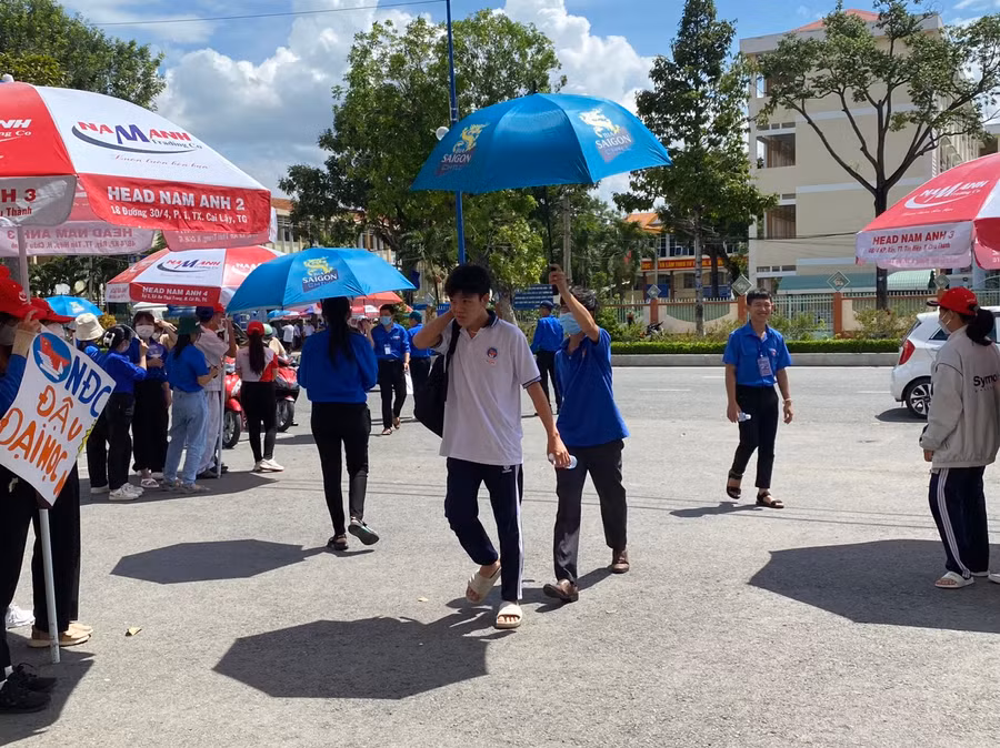 Tình nguyện viên che ô cho thí sinh vào trường thi.