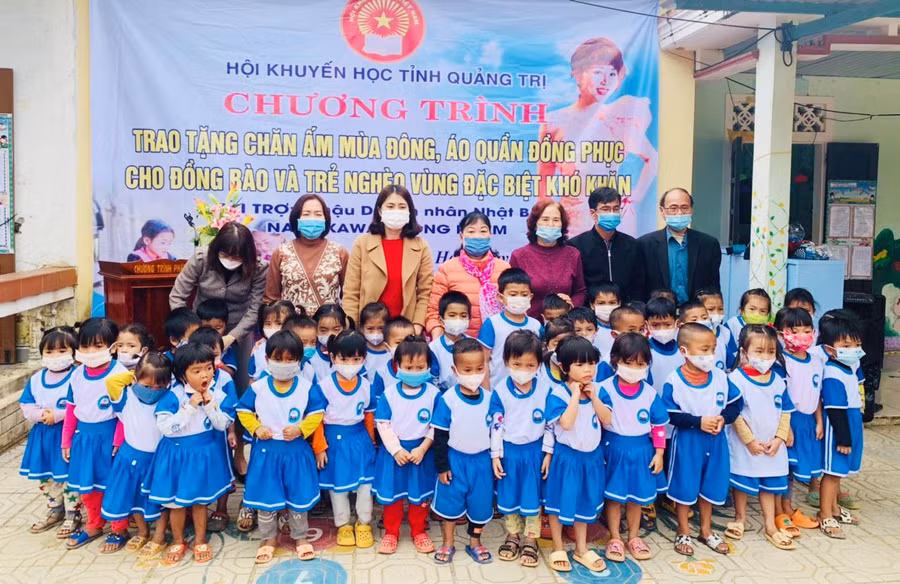 Cô Nguyễn Thị Hồng Vân (quàng khăn đứng giữa hàng sau cùng) trao tặng áo quần đồng phục cho học sinh ở huyện vùng núi Hướng Hóa.