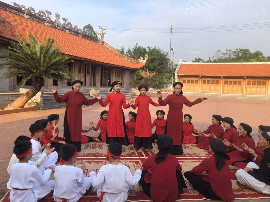 Các nghệ nhân dạy học sinh Trường Tiểu học Kim Đức học hát Xoan tại di tích miếu Lãi Lèn.