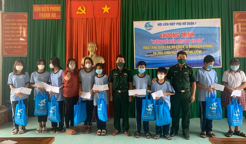 Cán bộ Đồn Biên phòng Thạnh An phối hợp với nhà hảo tâm tặng quà học sinh nghèo. 