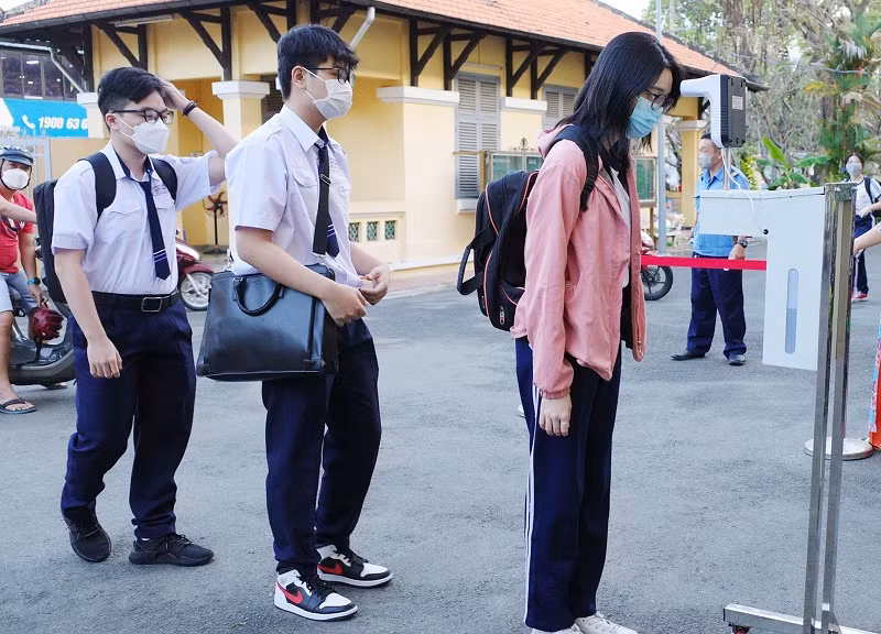 Học sinh đo thân nhiệt và khử khuẩn tay trước khi vào lớp tại Trường THPT Nguyễn Thị Minh Khai, TPHCM.