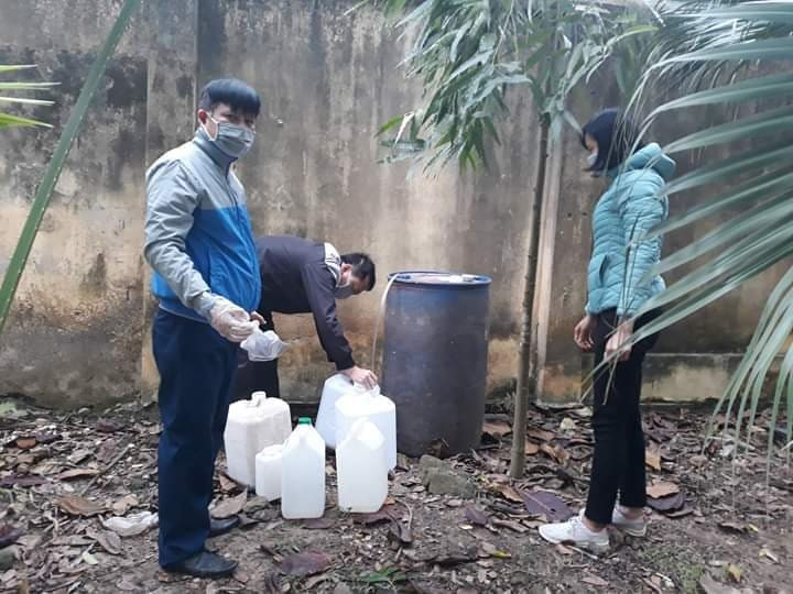 Thầy giáo Dương Khánh Toàn phân chia cồn đem đến cho giáo viên các trường lau chùi bàn ghế học sinh.