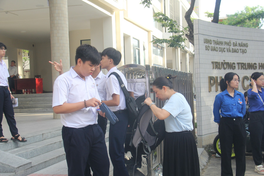 Một phụ huynh kiểm tra giấy tờ tùy thân, vật dụng của con trước khi vào cổng trường thi. Một phụ huynh kiểm tra giấy tờ tùy thân, vật dụng của con trước khi vào cổng trường thi.