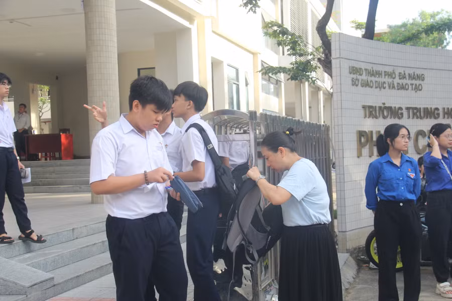 Một phụ huynh kiểm tra giấy tờ tùy thân, vật dụng của con trước khi vào cổng trường thi.