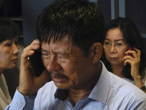 Family members of passengers on board AirAsia flight QZ 8501 talk on their phones while waiting for information inside a crisis centre at Juanda Airport in Surabaya, East Java