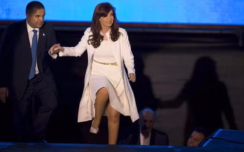 Nữ Tổng thống Argentina bước lên cầu thang với sự giúp đỡ của một người khác tại 1 buổi lễ kỷ niệm trong tháng 12/2014 ở Buenos Aires. Ảnh: AP