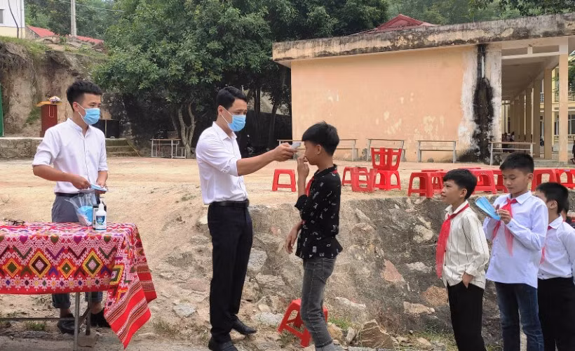 Thầy giáo kiểm tra thân nhiệt và cấp khẩu trang y tế cho học sinh Trường PTDTBT-THCS Mường Lý (Mường Lát, Thanh Hóa).