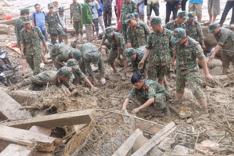 Lực lượng chức năng đang dùng tay đào bớt những lớp đất nhão nhoẹt để tìm kiếm nạn nhân.