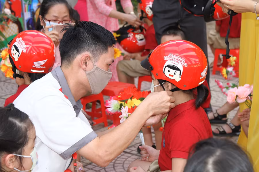 Nhân viên Cửa hàng Honda Hồng Phát đeo mũ bảo hiểm cho học sinh