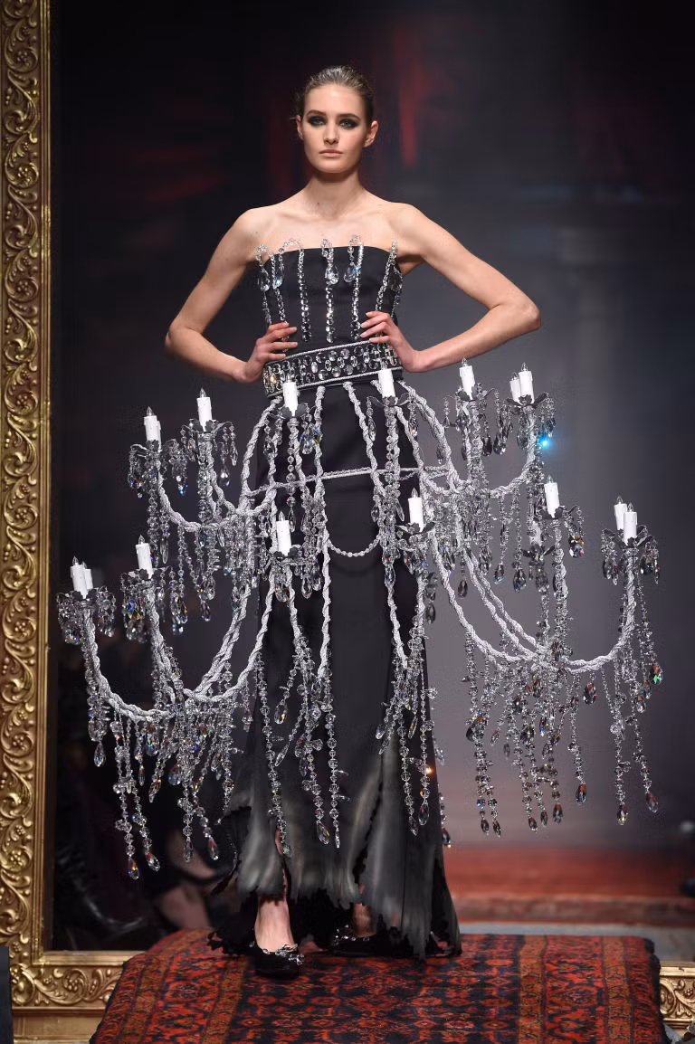 Milan Fashion Week mùa thu đông 2016 đang bước sang ngày thứ hai. Sau phần mở màn đẹp mắt của thương hiệu Gucci, đến lượt Moschino khiến giới mộ điệu đứng ngồi không yên với những ý tưởng độc đáo, táo bạo. Jeremy Scott cho người mẫu đeo chiếc đèn tường cỡ lớn lên sàn diễn.