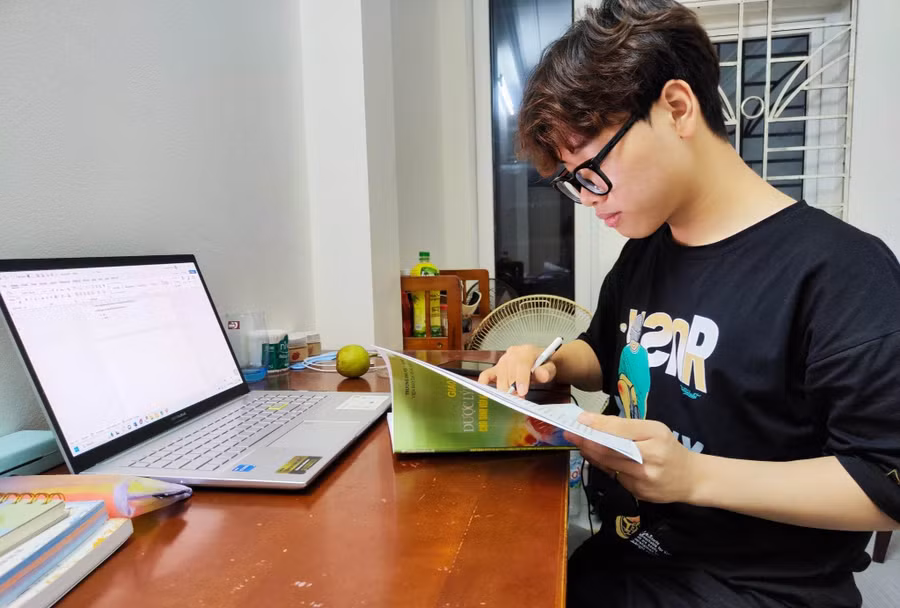 Phan Xuân Hành tranh thủ ôn bài buổi tối muộn sau khi đã kết thúc một ca dạy thêm từ 7 giờ tối đến 9 giờ 30 phút. Ảnh: NVCC