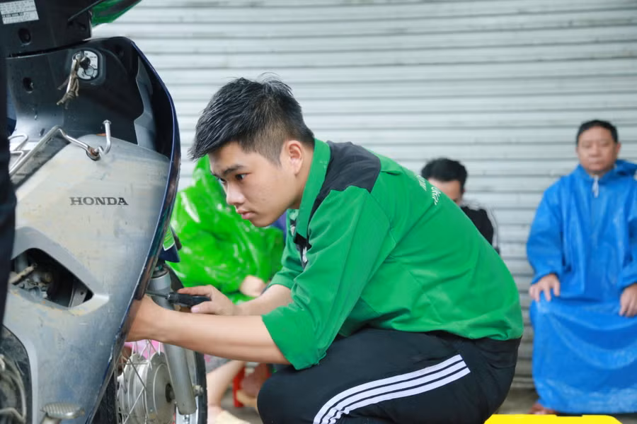 Thành viên của đội SOS tham gia sửa xe máy bị ngập nước cho người dân khu vực đường mẹ Suốt đều là sinh viên thuộc khối Kỹ thuật của Trường ĐH Đông Á.