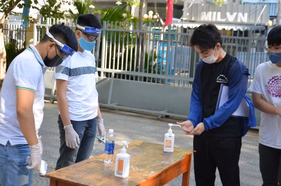 Sau khi được đo thân nhiệt, thí sinh rửa tay bằng nước sát khuẩn trước khi lê phòng thi nghe phổ biến các quy định phòng, chống dịch Covid - 19