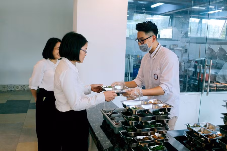 Học sinh thay nhau đảm nhận các vai trò: lấy đũa, thìa, bưng khay, chia cơm, lấy canh, hoa quả, vắt nước chanh; bạn thì kéo ghế, lau bàn mời thầy cô ngồi. Những đôi tay làm việc nhanh thoăn thoắt, hết sức chuyên nghiệp.