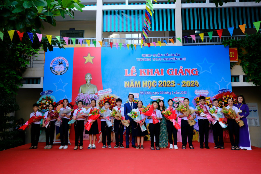 Ban giám hiệu Trường THCS Nguyễn Huệ tặng hoa cho đại diện học sinh khối lớp 6.