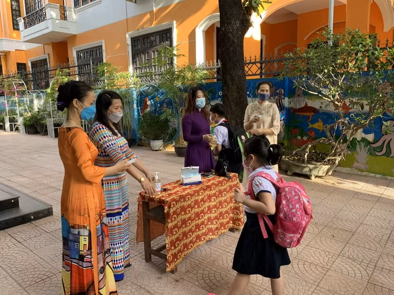 Kiểm tra thân nhiệt cho học sinh trước khi đến trường.