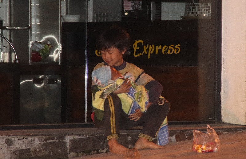 Một bé trai đang ôm em nhỏ ngủ gật gù trên tay lúc 23 giờ trên đường Cầu Mây, thị xã Sa Pa. Một bé trai đang ôm em nhỏ ngủ gật gù trên tay lúc 23 giờ trên đường Cầu Mây, thị xã Sa Pa.