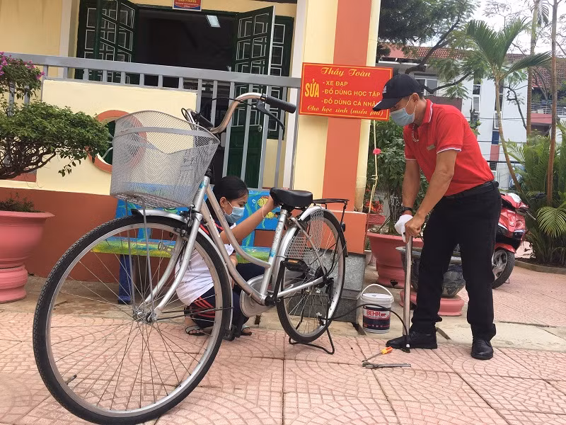 Thầy Toàn bơm xe cho học sinh. Ảnh: NVCC