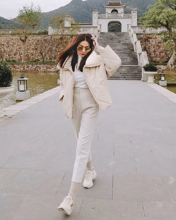 Xuống phố ngày lạnh, Thanh Hằng diện những item ngập tràn sắc trắng. Siêu mẫu mix áo cổ lọ với quần cạp cao, khoác ngoài là chiếc áo phao siêu ấm áp, rồi phối phụ kiện là giày thể thao có tông màu ăn ý.