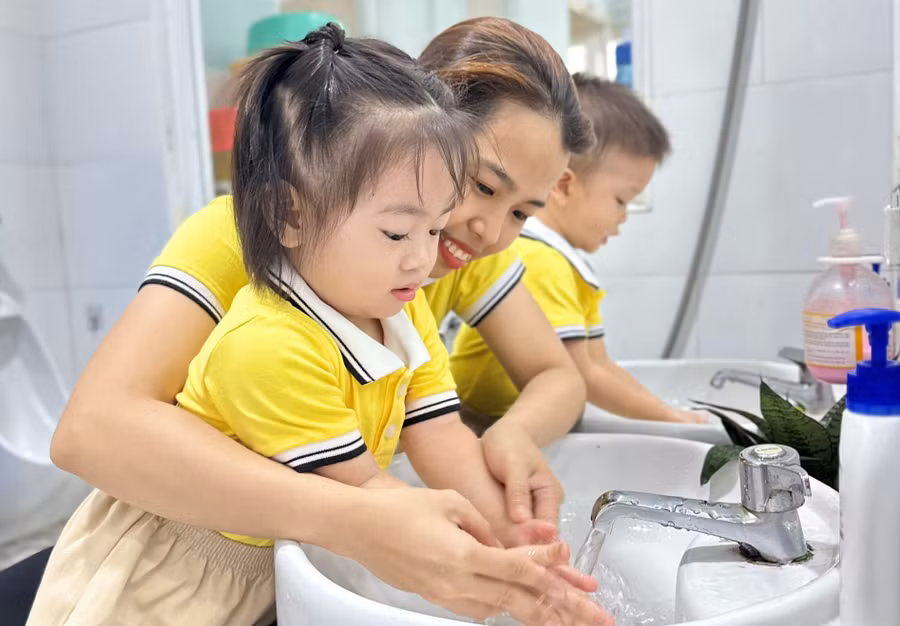 Giáo viên Nhóm trẻ Hồng Hà hướng dẫn trẻ rửa tay trước khi ăn trưa. Ảnh: Minh Anh