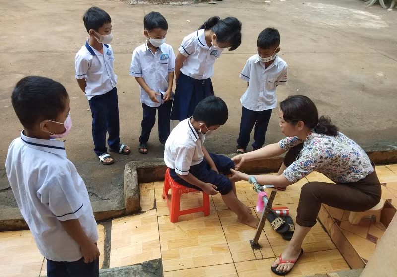 Giáo viên Trường Tiểu học Lê Lợi, buôn M’Hăng, xã Cư Huê, huyện EaKar (Đắk Lắk) hướng dẫn học sinh rửa tay chân. Ảnh: NTCC