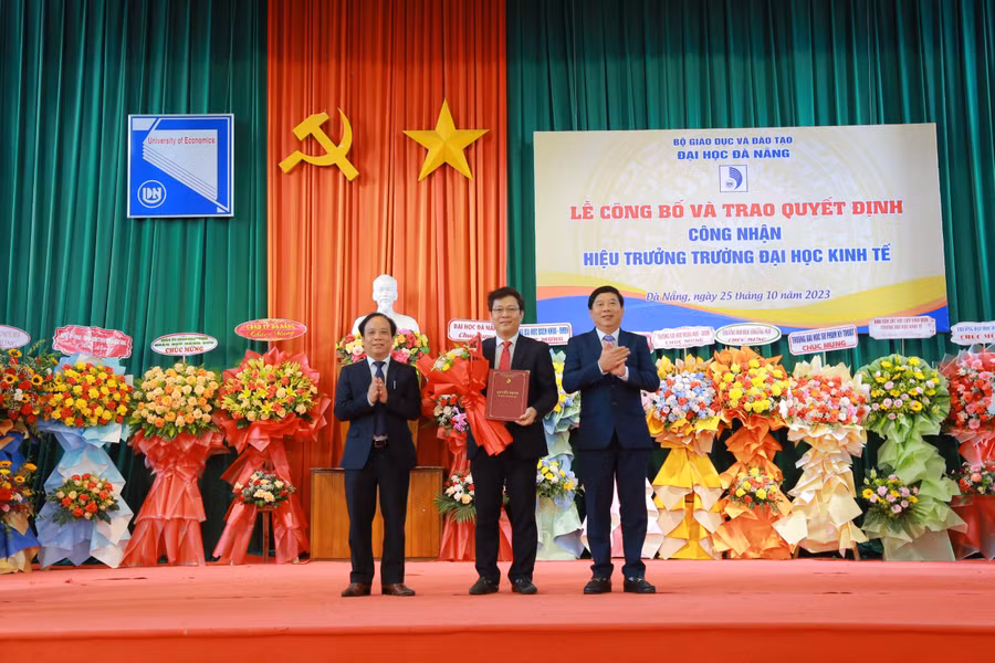 Giám đốc ĐH Đà Nẵng (trái) và Chủ tịch Hội đồng trường Trường ĐH Kinh tế (phải) trao quyết định công nhận Hiệu trưởng cho PGS.TS Lê Văn Huy. 