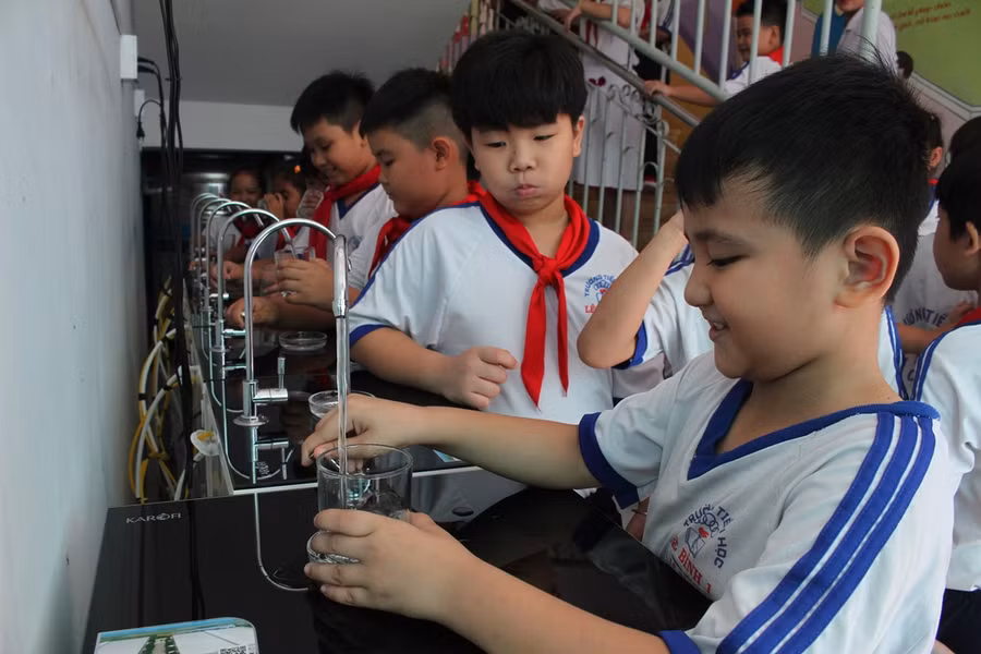 Các em HS uống nước tinh khiết từ máy lọc.