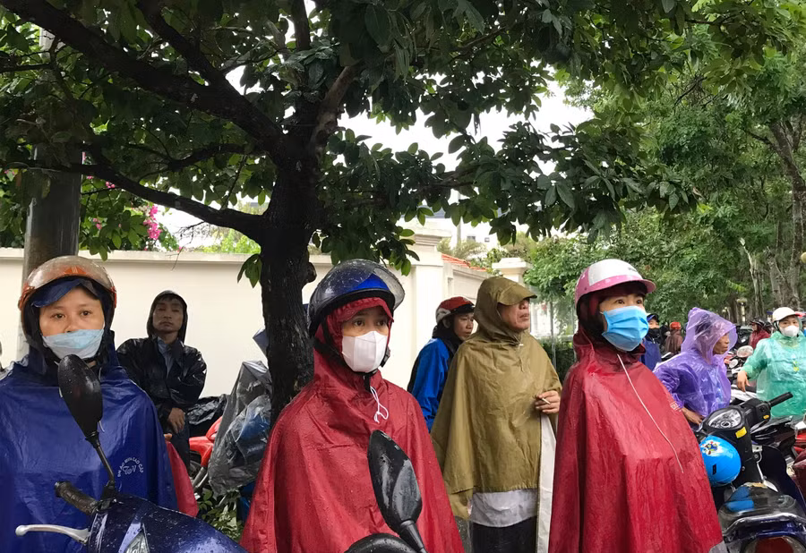 Chị Lê Thị Thảo (thứ 2 hàng trên từ trái qua) thấp thỏm đội mưa đợi con bên ngoài trường thi.