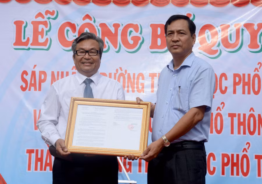 Phó Chủ tịch UBND tỉnh Cà Mau Trần Hồng Quân trao Quyết định ghép trường cho Hiệu trưởng Nguyễn Xuân Lai