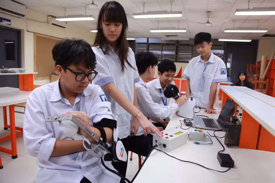 Nhóm học sinh Trường THPT chuyên Hà Nội - Amsterdam trong thời gian thực hiện dự án “Thiết bị thông minh hỗ trợ phục hồi chức năng cho người hạn chế vận động sau tai biến”. Ảnh: Lan Anh