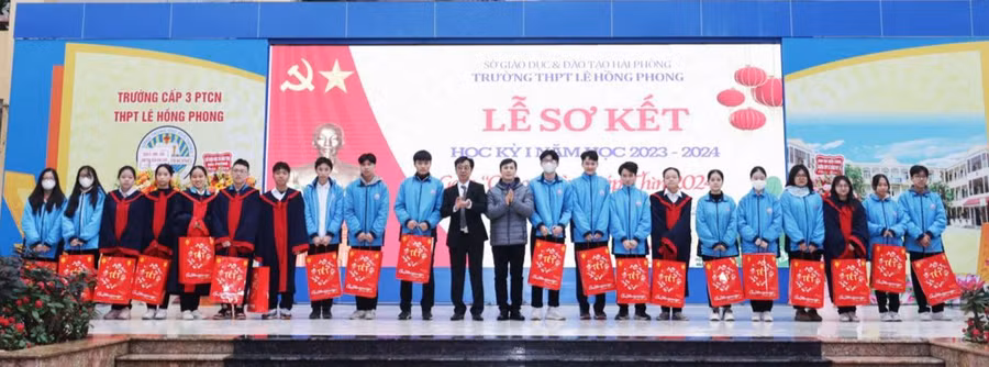 Học sinh vượt khó vươn lên trong học tập nhận quà từ lãnh đạo nhà trường.