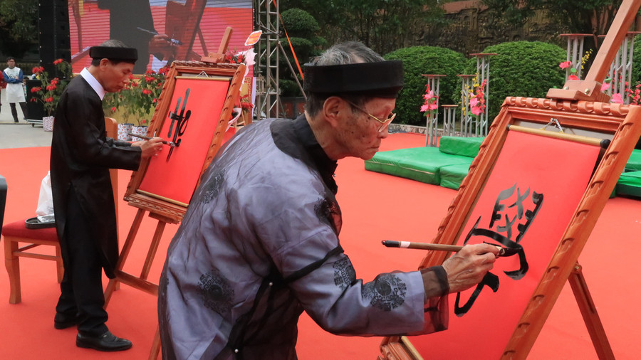 Các nghệ nhân viết chữ &quot;Học&quot; bằng thư pháp chữ quốc ngữ và chữ Nho.