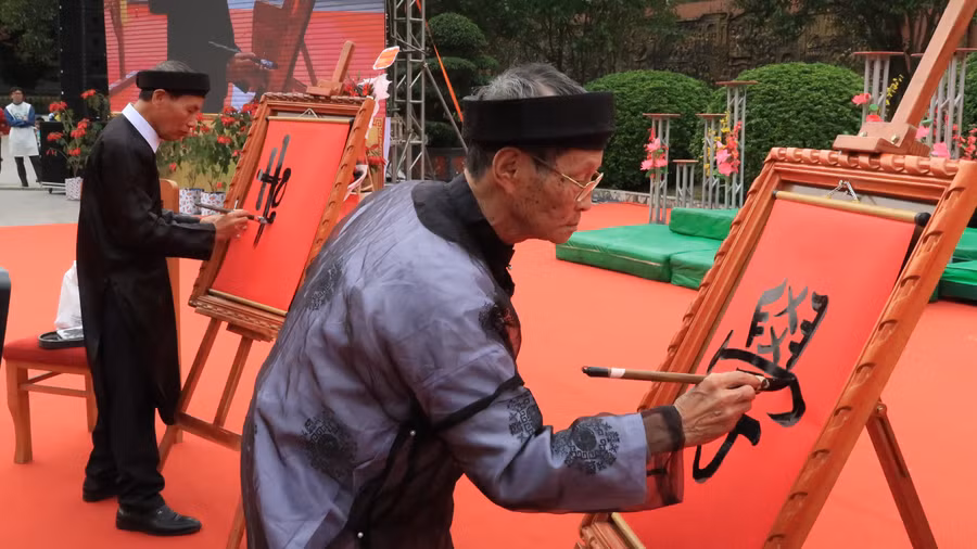 Các nghệ nhân viết chữ "Học" bằng thư pháp chữ quốc ngữ và chữ Nho.