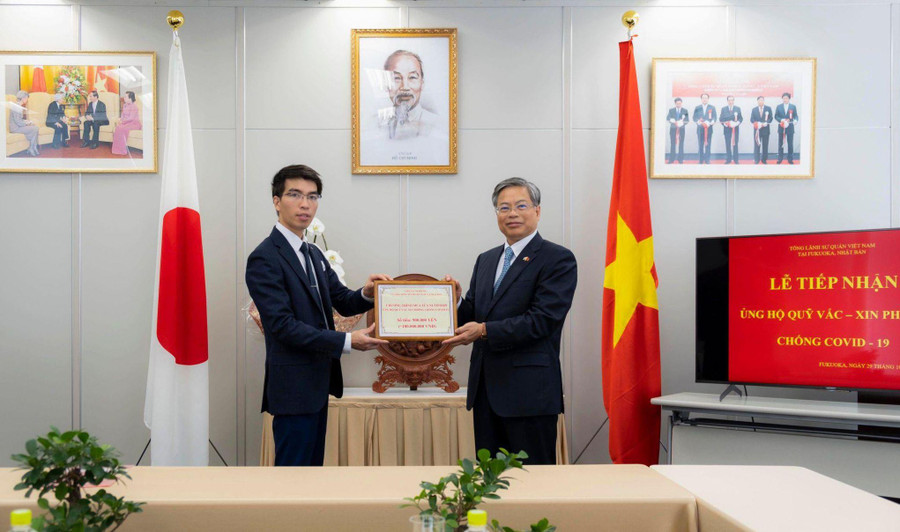 Anh Trần Nhân Đồng (bên trái) trao tặng số tiền thu được từ chương trình bán sữa cho Tổng Lãnh sự quán Việt Nam tại tỉnh Fukuoka gửi về Quỹ vắc-xin của Việt Nam. Ảnh: NVCC