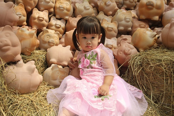 Em bé xinh xắn khá lạ lẫm khi nhìn thấy những con heo đất.