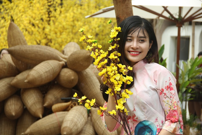 Cô gái trẻ làm duyên với cành mai.