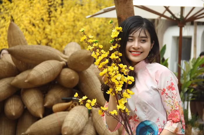 Cô gái trẻ làm duyên với cành mai.