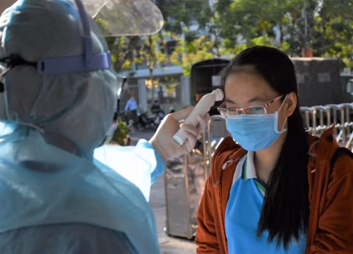 Các thí sinh chuẩn bị bước vào Kỳ thi tốt nghiệp THPT 2020 tại Đà Nẵng được cán bộ y tế đo thân nhiệt trước khi vào phòng nhận phiếu thông tin xét nghiệm.