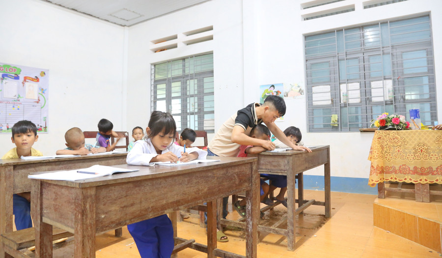 Thầy Hồ Đức Trung, phụ trách lớp 1 hướng dẫn các em nắn nót từng chữ. Ảnh: Đ.Đức