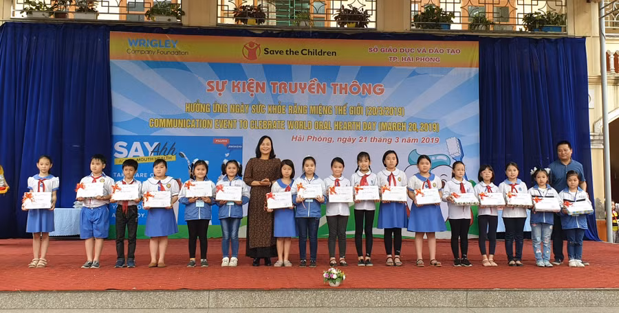 Bà Đỗ Thị Hòa, Phó Giám đốc Sở GD&ĐT Hải Phòng cùng đại diện Tổ chức Cứu trợ trẻ em Quốc tế trao quà cho học sinh