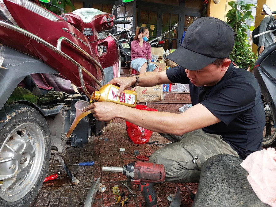 Thay nhớt xe máy cho người dân, sinh viên sau khi xe bị ngập nước.