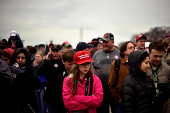 Một người ủng hộ Donald Trump đội chiếc mũ đỏ có khẩu hiệu "Make America Great Again" trong lễ nhậm chức Tổng thống của ông ở Washington ngày 20/1. Ảnh: Reuters.