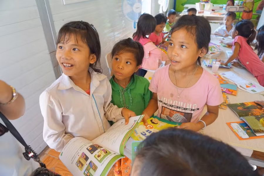 Em Lò Thị Thư (9 tuổi, dân tộc Cống – áo trắng) được một cô giáo Ban Mai tranh thủ dạy một số câu chào bằng tiếng Anh. 