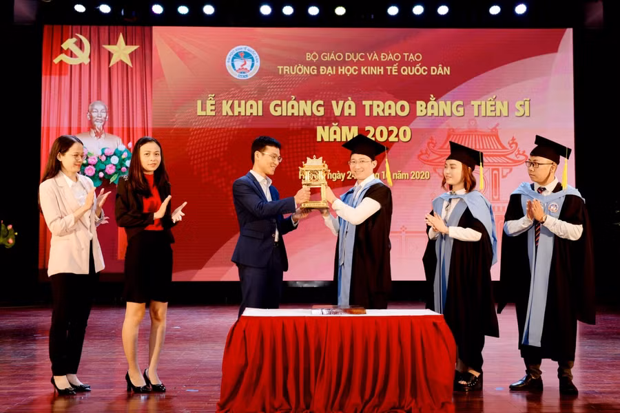 Các tân tiến sĩ trao biểu trưng của chương trình đào tạo trình độ tiến sĩ cho NCS khoá 41 tại buổi Lễ