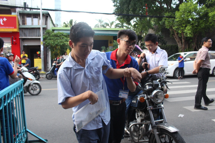 Một thí sinh đặc biệt tại điểm thi Trường THCS Colette được sinh viên tình nguyện hỗ trợ vào điểm thi