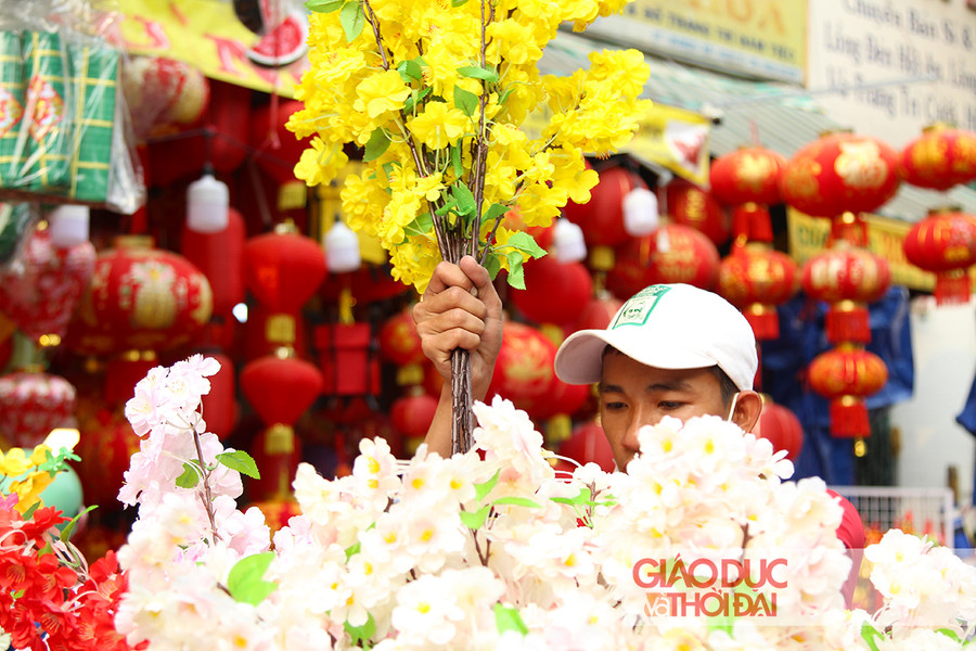 Từng cành hoa mai, hoa đào bằng vải được người bán sắp xếp xen kẽ, khoe sắc khắp một đoạn đường dài.