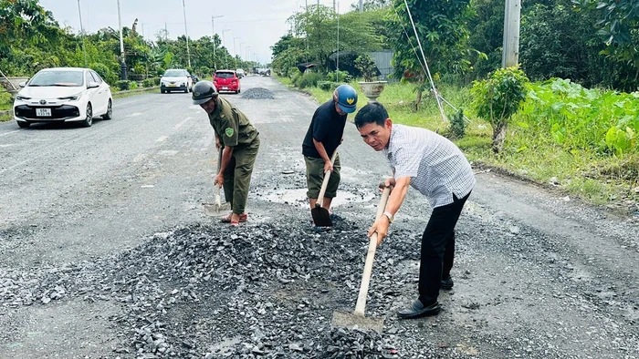 Ông Lê Bá Toàn (áo sơ mi) cùng lực lượng dân quân trong khu vực vá đường Nguyễn Văn Cừ.