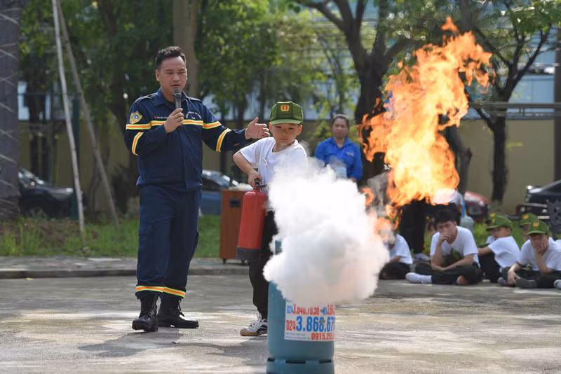 Thiếu tá Nguyễn Danh Luân - Cục Phòng cháy chữa cháy và Cứu hộ cứu nạn hướng dẫn các em thực hành dập lửa bằng bình chữa cháy. Chiến sĩ nhí học cách thoát hiểm